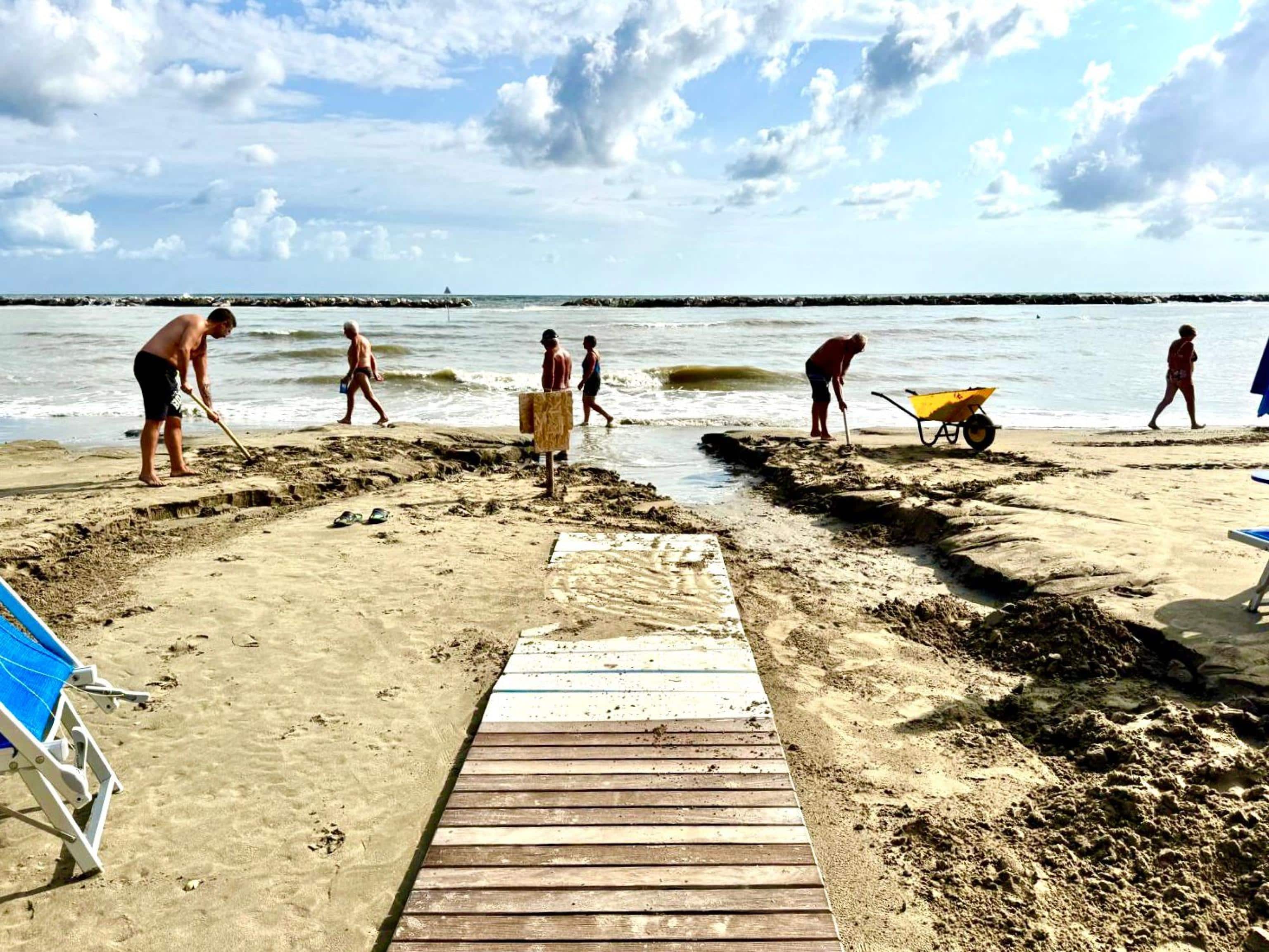 Alcuni bagnanti intervengono per riportare alla normalità una spiaggia di Igea Marina danneggiata dal temporale che si è abbattuto prima dell'alba sulla riviera romagnola. Igea Marina, 24 agosto 2025 ANSA