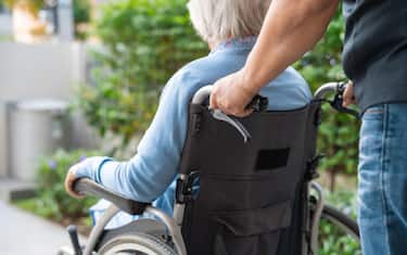 Caregiver help and care Asian senior or elderly old lady woman patient sitting on wheelchair at nursing hospital ward, healthy strong medical concept