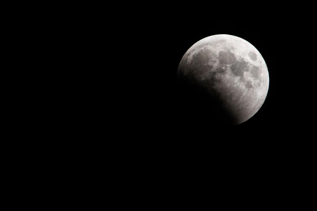 MERRITT ISLAND, FLORIDA - MARCH 14: The full Worm Moon enters the umbra ahead of its total eclipse on March 14, 2025 in Merritt Island, Florida. A total lunar eclipse transpires when the sun, Earth and moon orient in a straight line with Earth in the middle. The Earth's shadow engulfs the surface of the moon, causing it to radiate scarlet hues of light from the sun. (Photo by Brandon Bell/Getty Images)