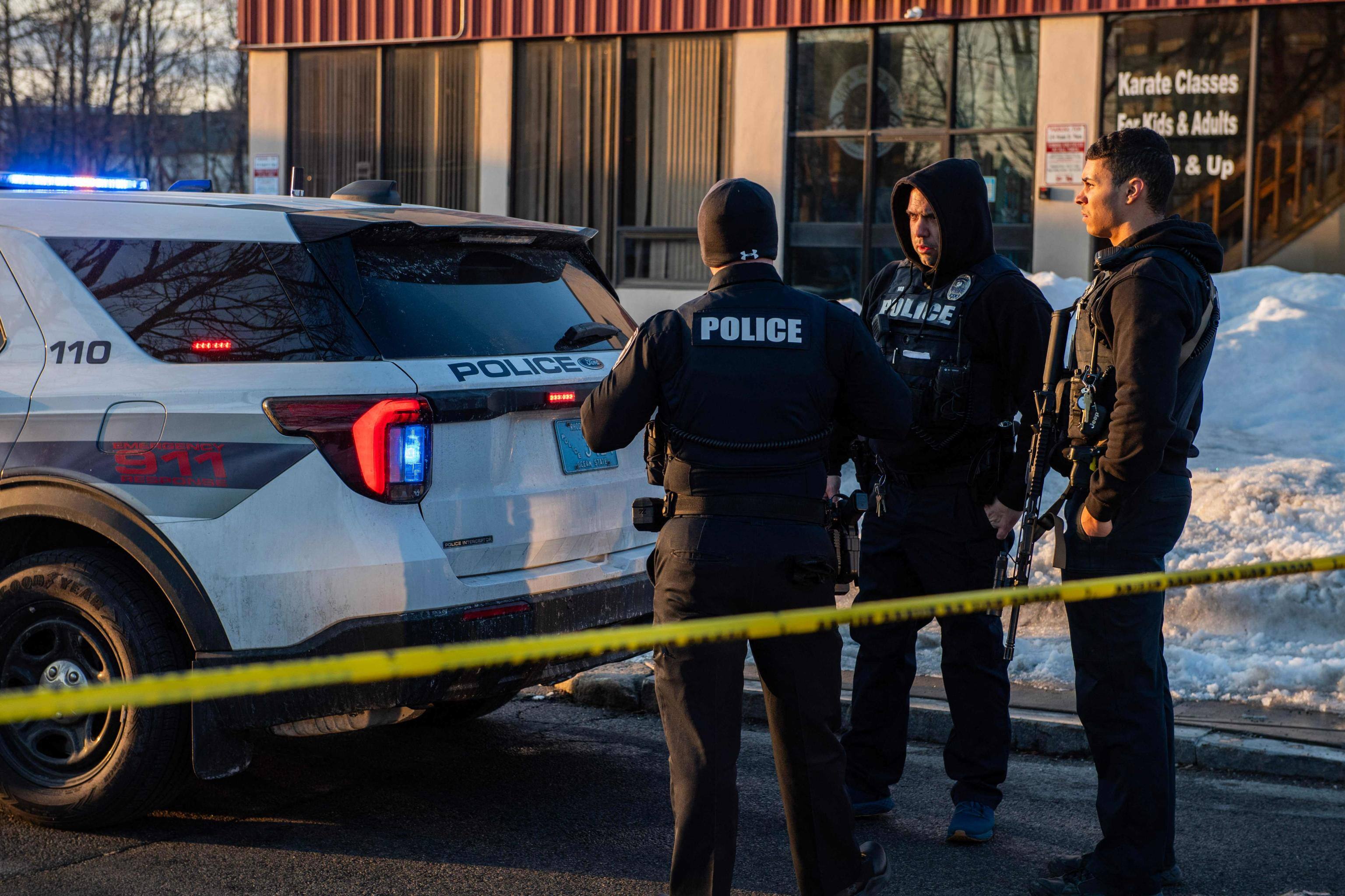 Police stand outside the perimeter they created around the Dennis M Lynch Arena where a shooting occurred earlier today in Pawtucket, Rhode Island, on February 16, 2026. At least two people were killed and three wounded in a shooting at an ice rink in the northeastern US town of Pawtucket on Monday, authorities said, with social media footage showing frightened teenagers fleeing the sound of gunshots. "We have three deceased. The suspect, and then we have two victims, and then we have three at the hospital," said Pawtucket police chief Tina Goncalves told reporters after the incident. She added that initial investigations suggested the shooting was targeted and "may be a family dispute." (Photo by Joseph Prezioso / AFP)