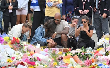 epa12595447 Mourners react after placing flowers at a makeshift memorial at Bondi Beach in Sydney, Australia, 16 December 2025. Australia is in mourning following an attack on the Jewish community's Hanukkah festival celebrations on 14 December that left at least 16 people dead, including one gunman.  EPA/MICK TSIKAS AUSTRALIA AND NEW ZEALAND OUT