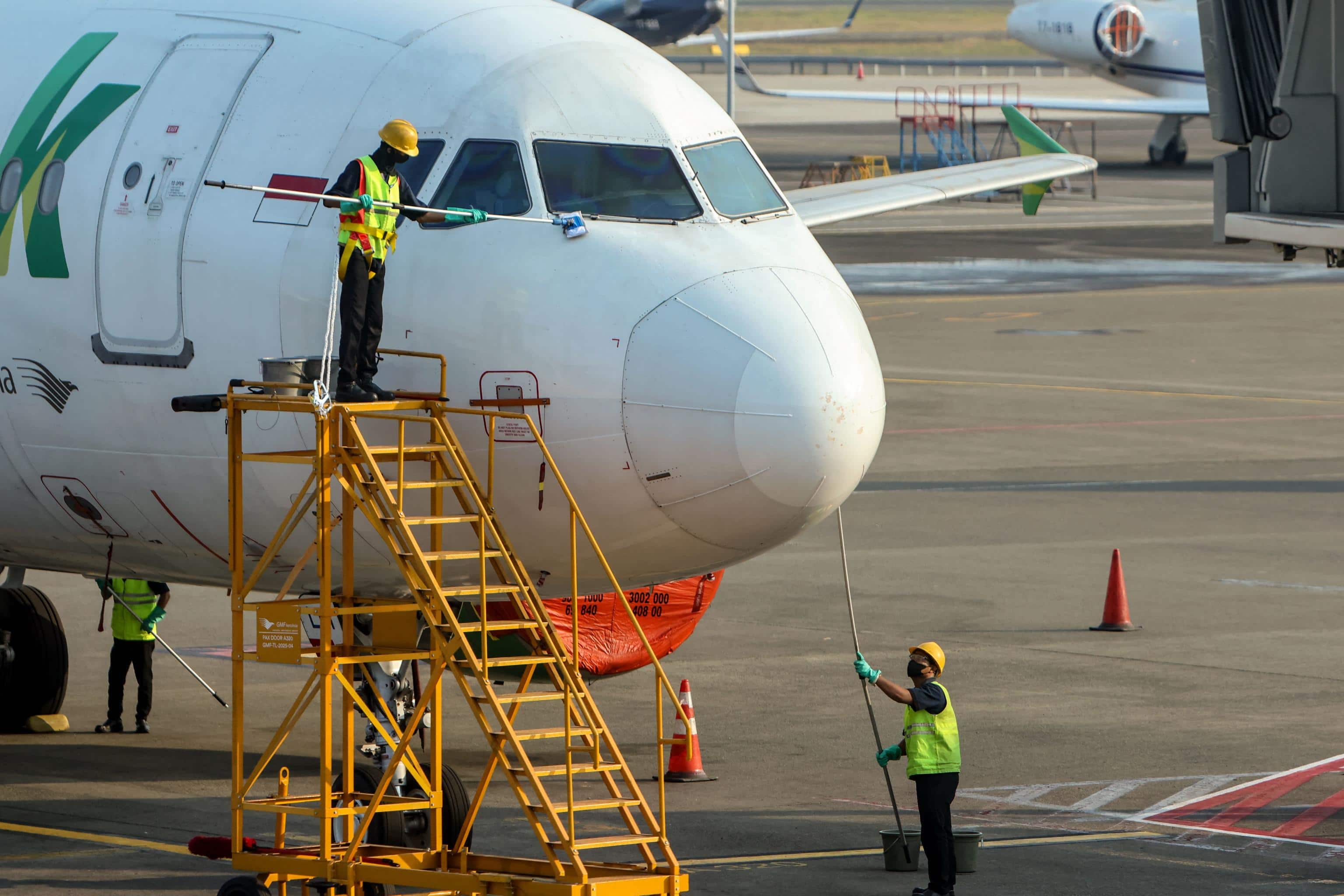 Workers wipe down a Citilink Airbus A320 aircraft parked on the apron of the Soekarno-Hatta airport in Tangerang on September 7, 2026, after flight operations were suspended following the eruption of Mount Anak Krakatau. Indonesia's main airport postponed reopening on September 7 after halting operations following a volcanic eruption that left hundreds of thousands of passengers stranded. (Photo by SYARIEF Akbar / AFP)