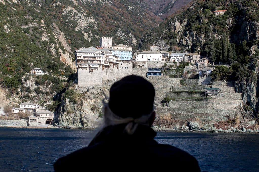 MOUNT ATHOS,GREECE - DECEMBER 5: A monk looks toward Dionysiou monastery from a ferry boat before arriving on to the holy mountain of Mount Athos on December 5, 2016 in Greece. Dionysiou, which was built in the 14th century, is one of the twenty monasteries on the peninsula. (Photo by Rick Findler/Getty Images)